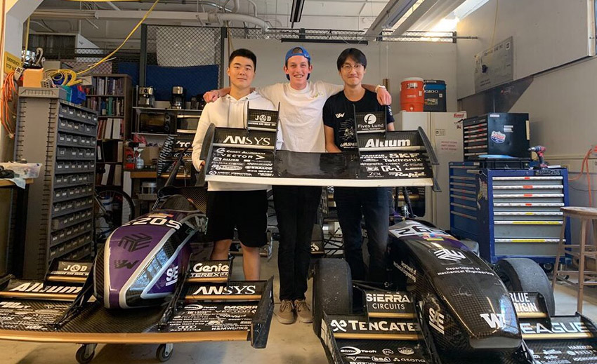 Jerry Hu, Sam Reissmann and Michael Chi posing with two race cars