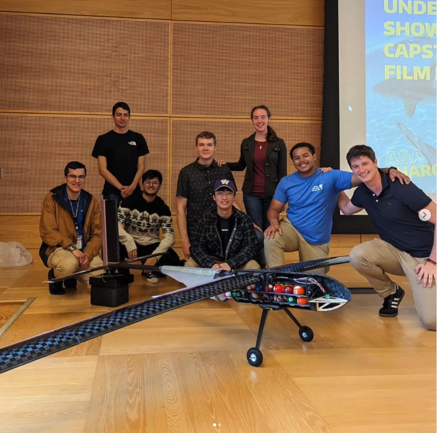 Group of people posing behind a remote controlled aircraft