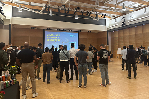 Group of people standing in a room during a research showcase event