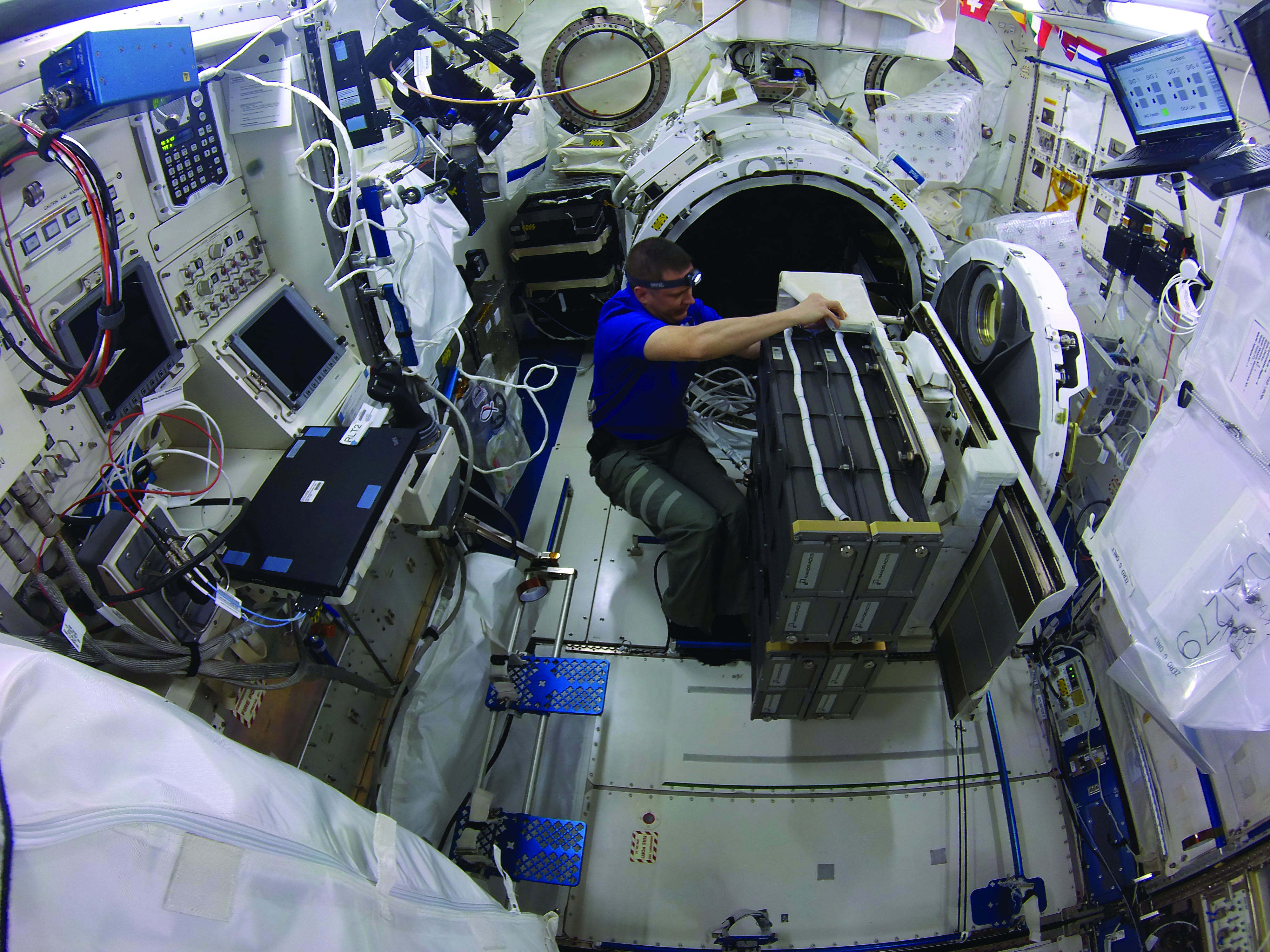 astronaut Jack Fischer loading a set of stacked cubesat deployers into the JEM airlock for external installation