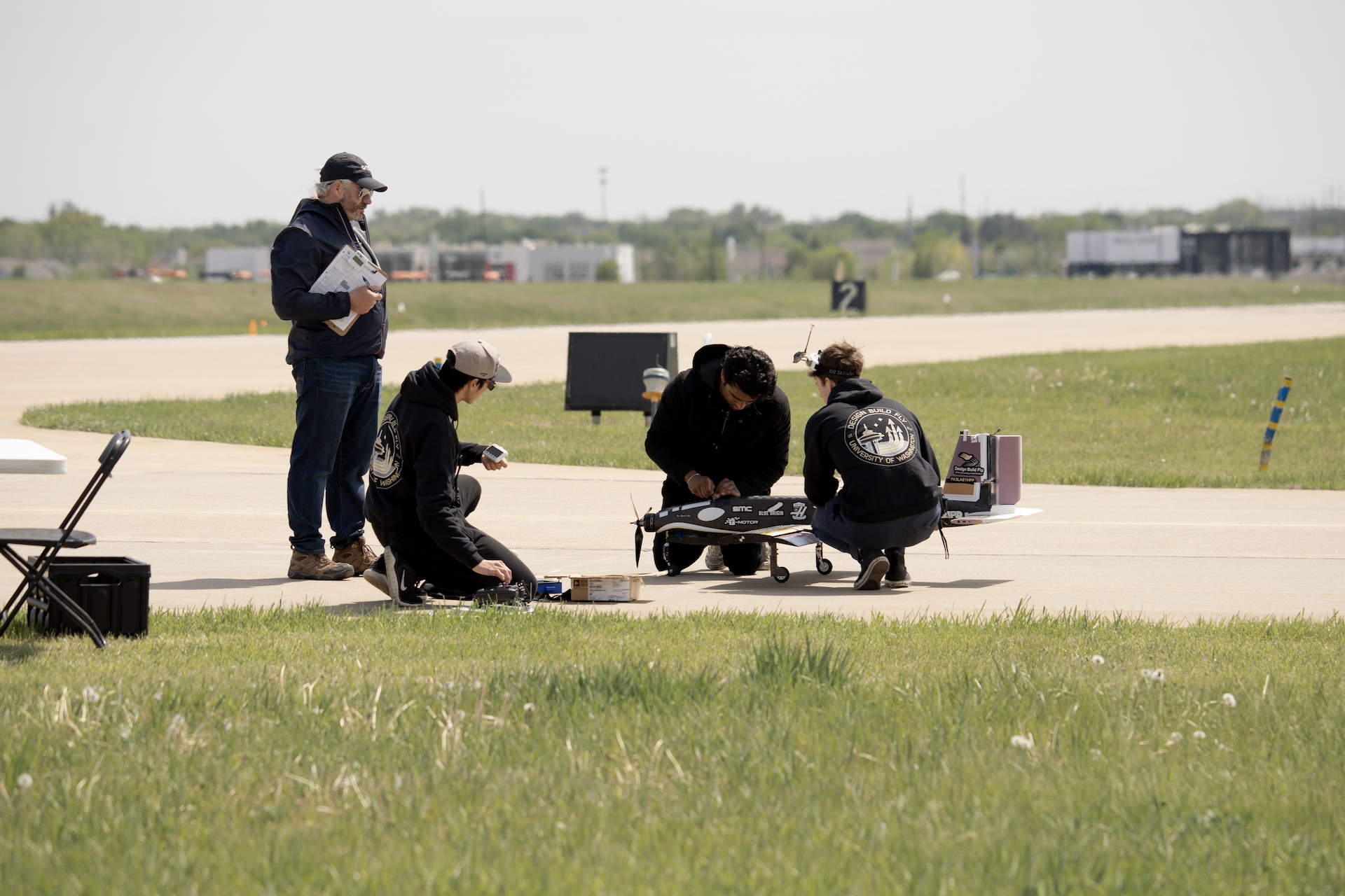 Group of people adjusting a remote control aircraft outdoors