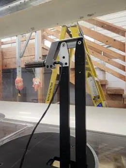 Black metal stand on a circular platform with a staircase and ladder in the background.